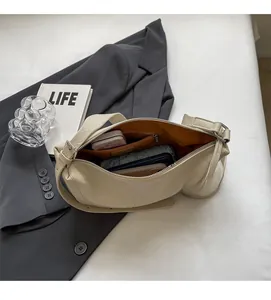 Detailopname van het ruime binnenvak van deze chique beige halve maanvormige schoudertas