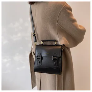 Detailed view of a vintage black satchel bag with golden buckles and top handle