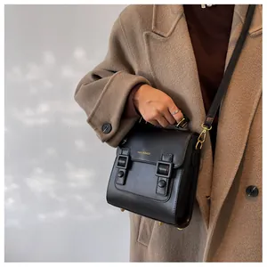 Close-up of a vintage black square bag with double buckles and a slender shoulder strap