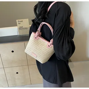 Détail du sac seau en paille avec anses en cuir rose et surpiqûres contrastées