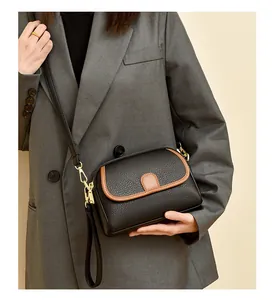 Chic black litchi leather crossbody bag with brown piping and gold hardware