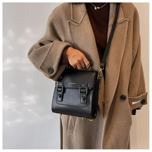 Detail of black vintage satchel bag with silver studs and buckle on khaki coat background