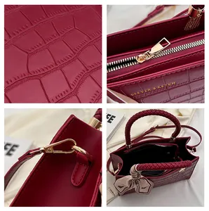 Detail view of burgundy crocodile pattern handbag with gold hardware and silk scarf accessory