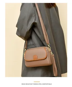 Detail of lychee pattern leather crossbody bag with contrast trim and gold hardware