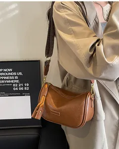 Caramel brown leather crossbody bag with wide woven strap and fringe tassel zipper detail