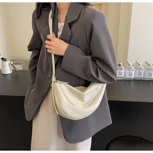 Detail van minimalistische beige halvemaantas met lederen textuur en verstelbare riem