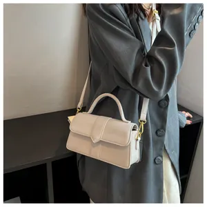 Détail d'un sac bandoulière blanc en similicuir avec garnitures dorées et un rabat