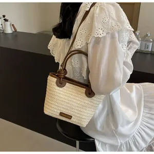 Détail du porté épaule et du profil latéral d'un sac en paille tressée et cuir chic