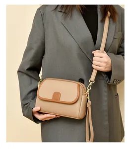 Detail shot of beige pebble grain leather crossbody bag worn with a gray suit