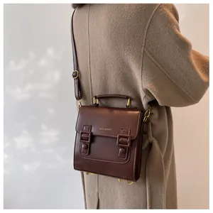 Detail of dark brown vintage satchel bag worn over a camel wool coat with shadow effects