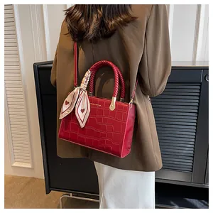 Detail view of red crocodile texture handbag with silk scarf and woven handle
