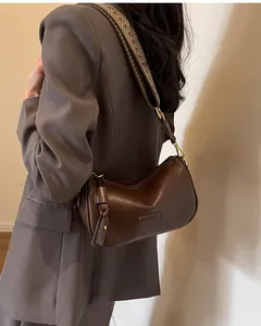 Brown vintage crossbody bag with ethnic woven strap shown on a model in a grey blazer