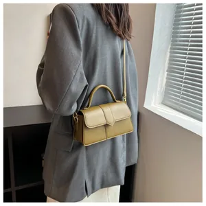 Vue détaillée du sac bandoulière en cuir vert olive porté par un mannequin en décor épuré