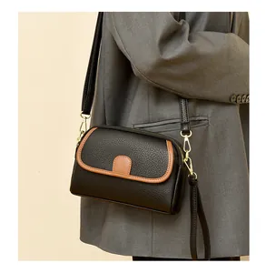 Detail of a vintage-style black lychee pattern leather crossbody bag on a grey blazer