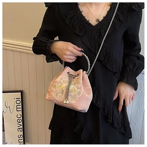 Dettaglio borsa a secchiello in velluto rosa con ricami dorati e coulisse decorata con perle