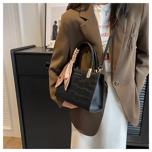Detail of black crocodile pattern handbag with braided handle and heart silk scarf