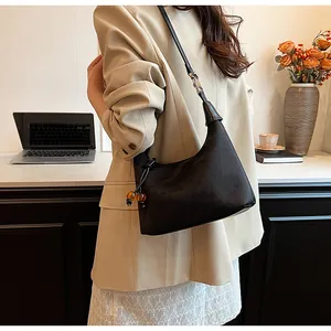 Detail of black beaded handbag with texture and brown bead charm on a beige blazer