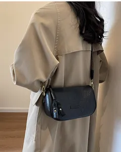 Detailed view of black vintage pleated shoulder bag with tassel and gold metal hardware