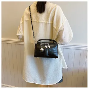 Bolso tipo caja negro con textura de cocodrilo y correa de cadena mostrado por una modelo