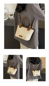 Détail du sac seau en paille contrastée avec poignées en cuir marron et étiquette de mode