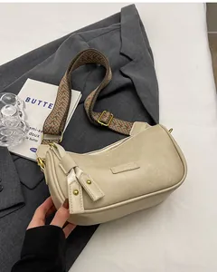 Close-up of cream half-moon PU leather bag with wide geometric woven shoulder strap