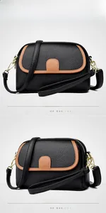 Detail of black lychee leather crossbody bag with brown trim and gold hardware