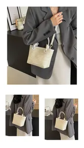 Détail d'un sac seau en paille tissée avec poignée et bandoulière en cuir blanc