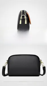 Detail of black pebbled leather crossbody bag with three golden zipper compartments