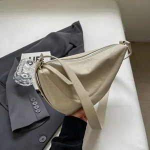 Detailweergave van de crèmewitte halve maan tas met zachte korrelige leertextuur
