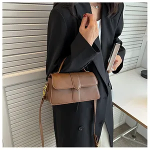 Détail d'un sac à bandoulière en cuir marron avec poignée et finitions dorées