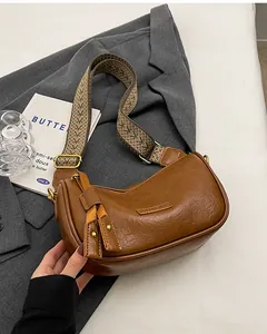 Detail of dark brown oil wax leather bag featuring bohemian strap and tassel charm