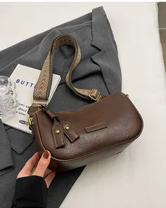Detail of dark brown semi-circular shoulder bag with jacquard strap and gold hardware