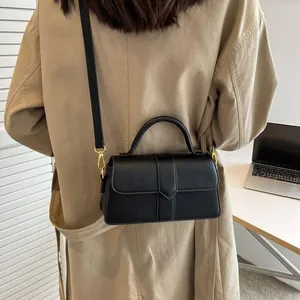 Détail d'un sac bandoulière en cuir noir porté par un mannequin dans un bureau