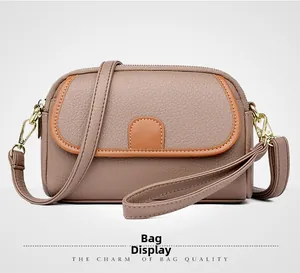 Detail of dusty pink pebbled leather shoulder bag with gold zippers and brown piping