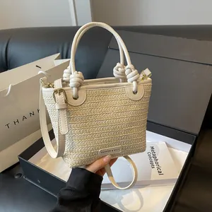 Sac seau en paille tressée blanc crème avec poignée nouée dans sa boîte cadeau