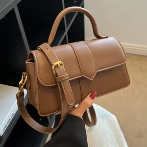 Sac bandoulière rétro en cuir marron avec design à lanières et finitions dorées chic