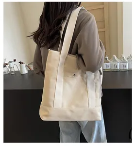 Dettaglio della borsa tote in tela bianco sporco con tasca frontale e bottone a pressione