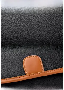 Macro detail of black litchi grain leather and brown contrast stitching on the handbag