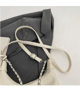 Detail of adjustable leather strap and silver chain on a beige hobo shoulder bag