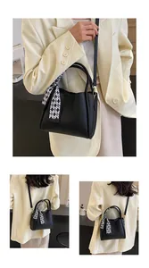 Detail of black pebbled leather handbag with double handles and checkered silk scarf