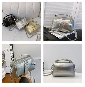 Detalle de mini bolsos caja metálicos en plata y oro con correas de cadena y doble cremallera