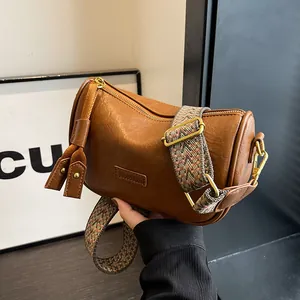 Vintage brown leather cylinder shoulder bag with a stylish geometric patterned wide strap