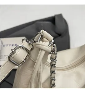 Detail of silver chain link and premium polished hardware on a beige leather bag