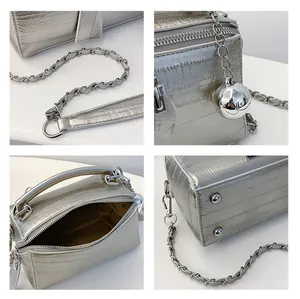 Detalles del bolso de cuero plateado mostrando la correa de cadena, cremallera y colgante
