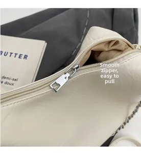 Detailed view of the smooth silver zipper and soft pleated texture on beige shoulder bag