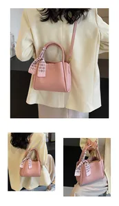 Detail of light pink pebble leather handbag with printed silk scarf and gold hardware