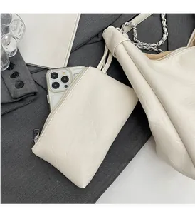 Detail of cream pleated leather bag set with silver chain and matching zipper pouch