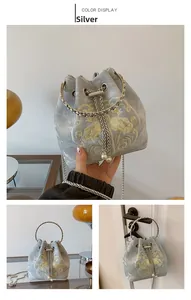 Dettagli del ricamo e del manico argentato della borsa a secchiello con coulisse di perle