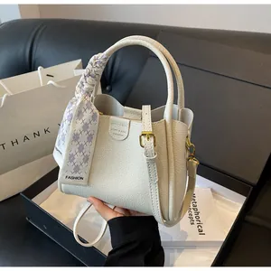 Detailed view of white lychee leather handbag with a purple silk scarf and gold hardware