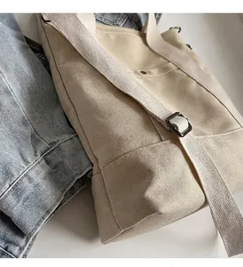 Dettaglio della borsa tote in tela color crema con tracolla regolabile e fibbia in metallo